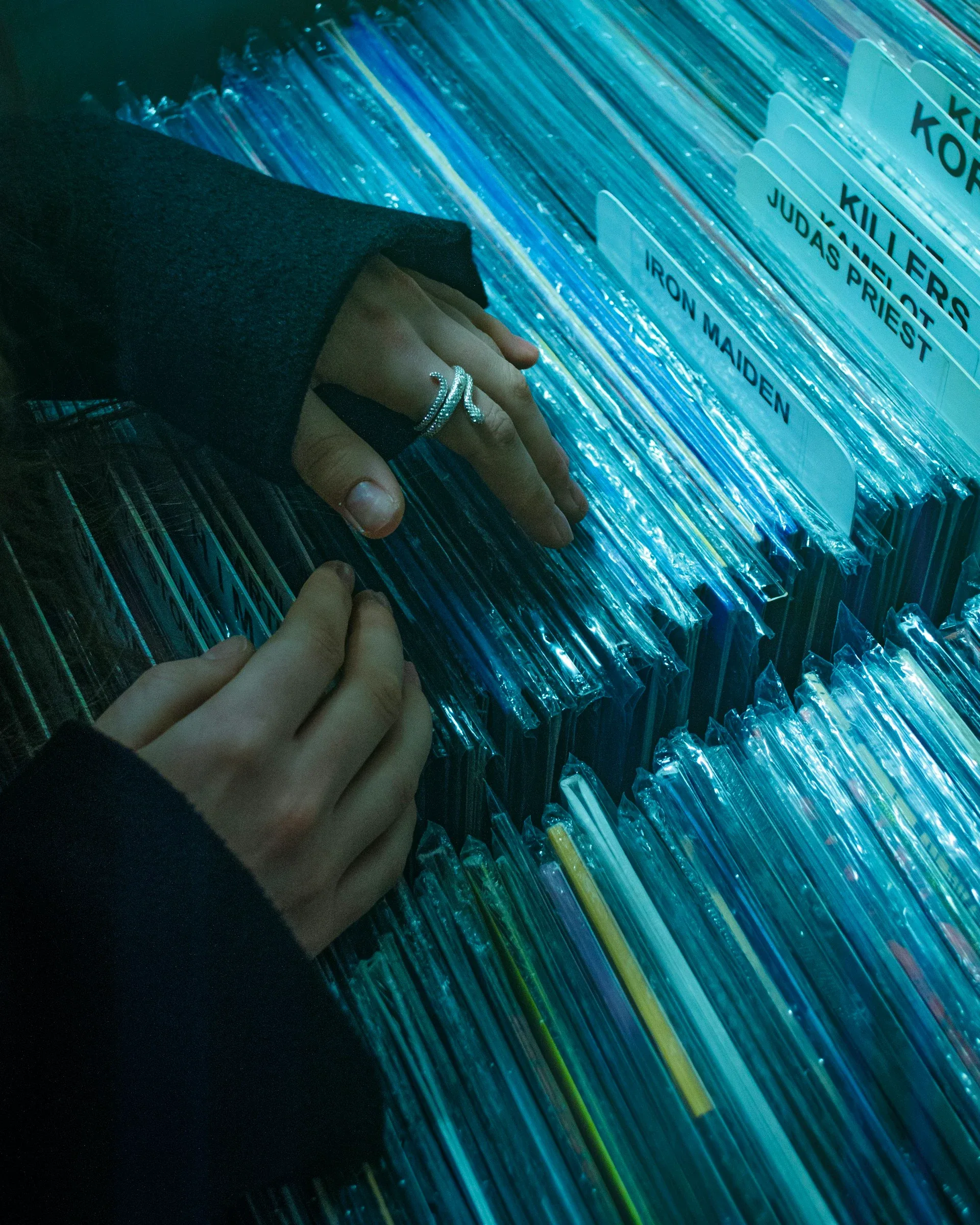 Hands flipping through vinyl records in the indie section of a record store